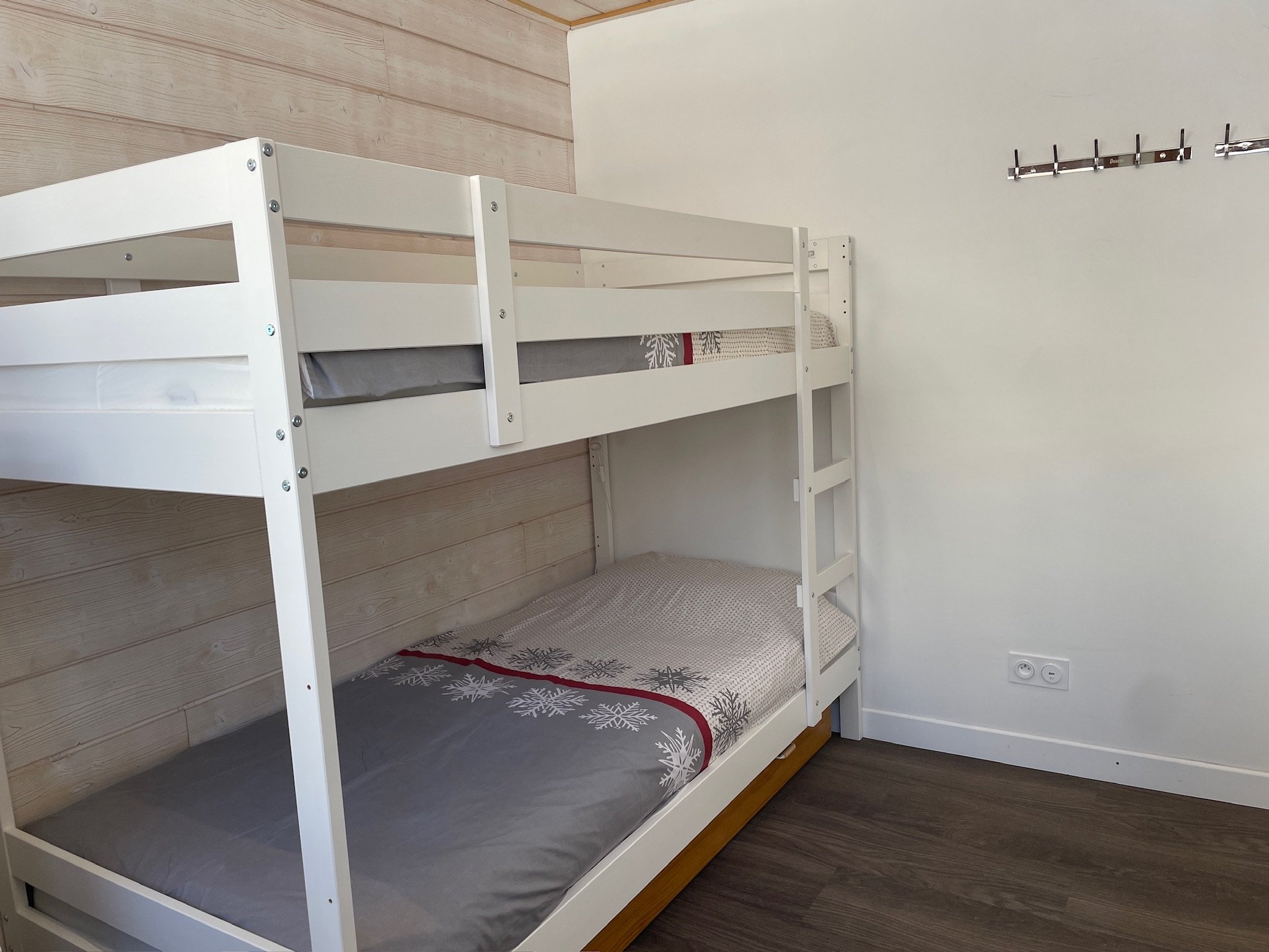 White bunk beds and coat hooks in the second bedroom