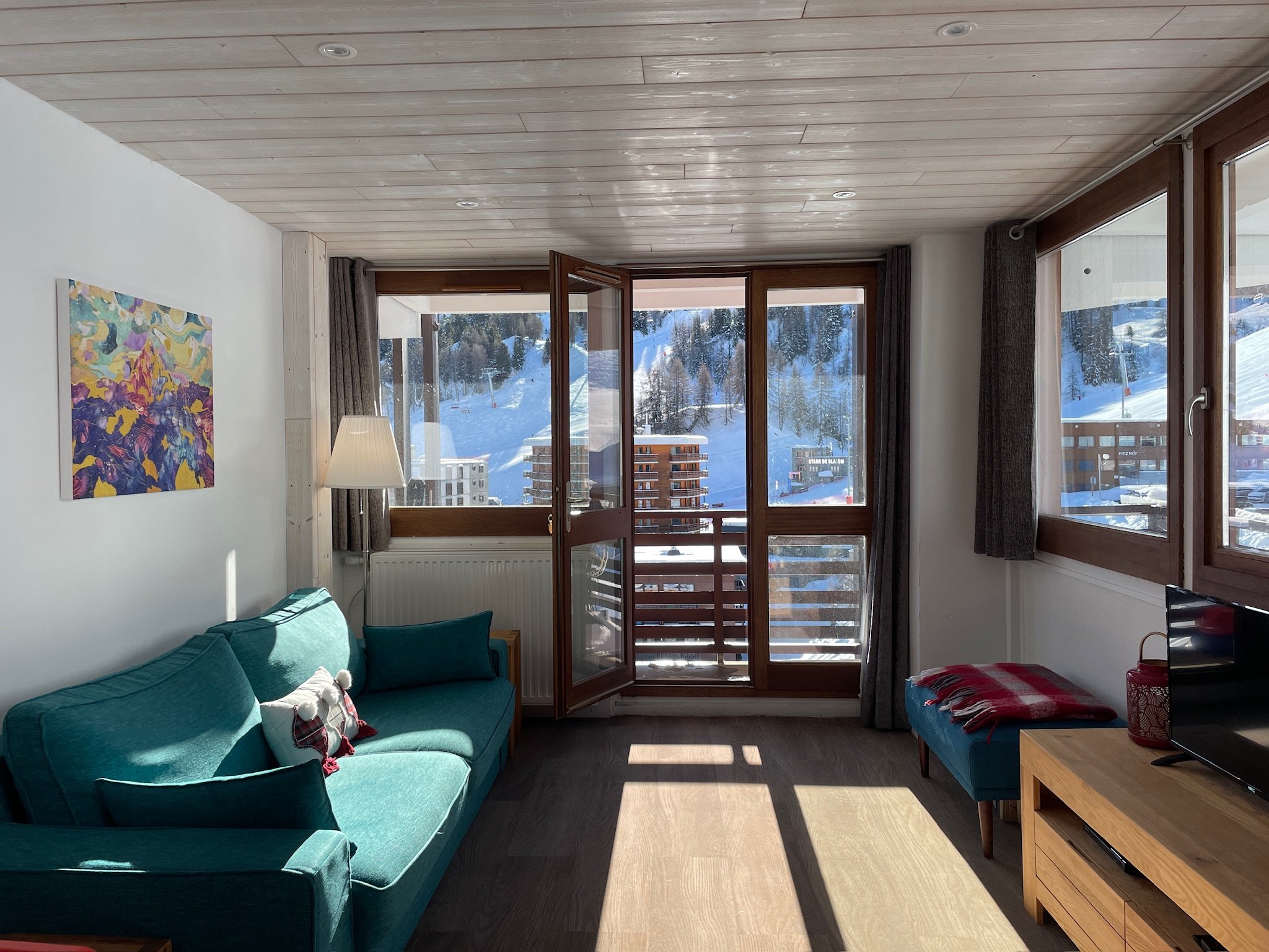 Living room at SnowBadgers with a wrap-around balcony looking onto snowy Plagne Centre