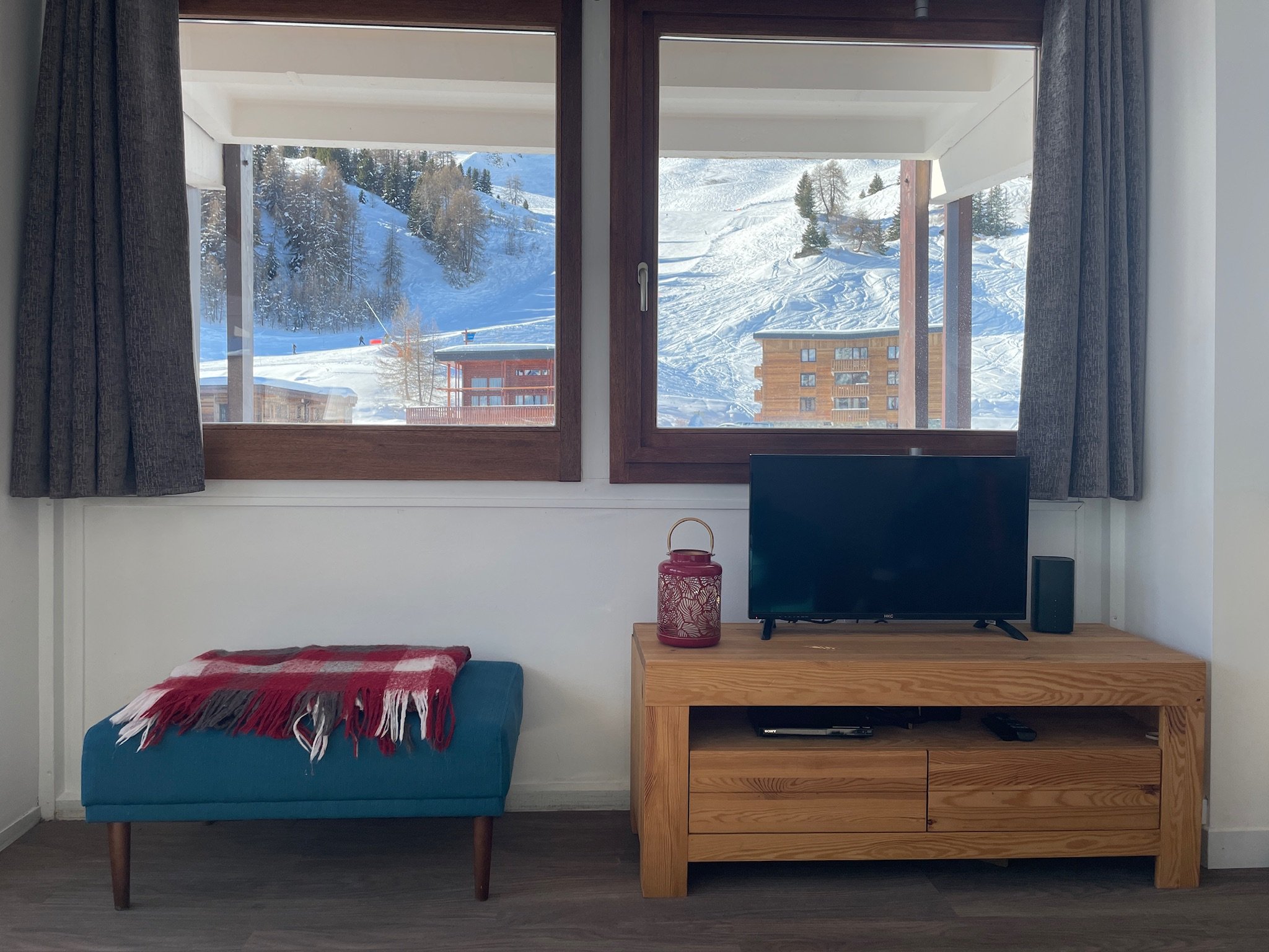 Television beneath windows looking onto the snowy slopes
